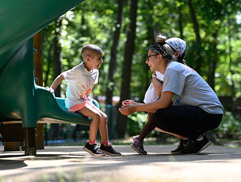 mom and daughter outside playing on a slide