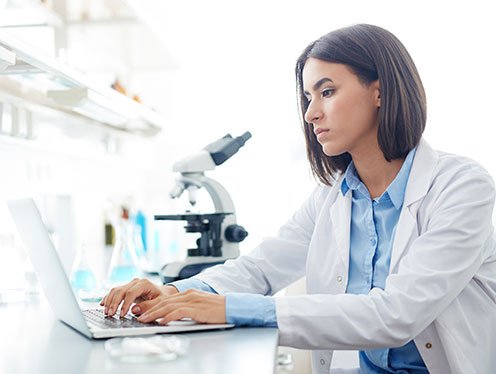 doctor with a microscope taking notes on a computer