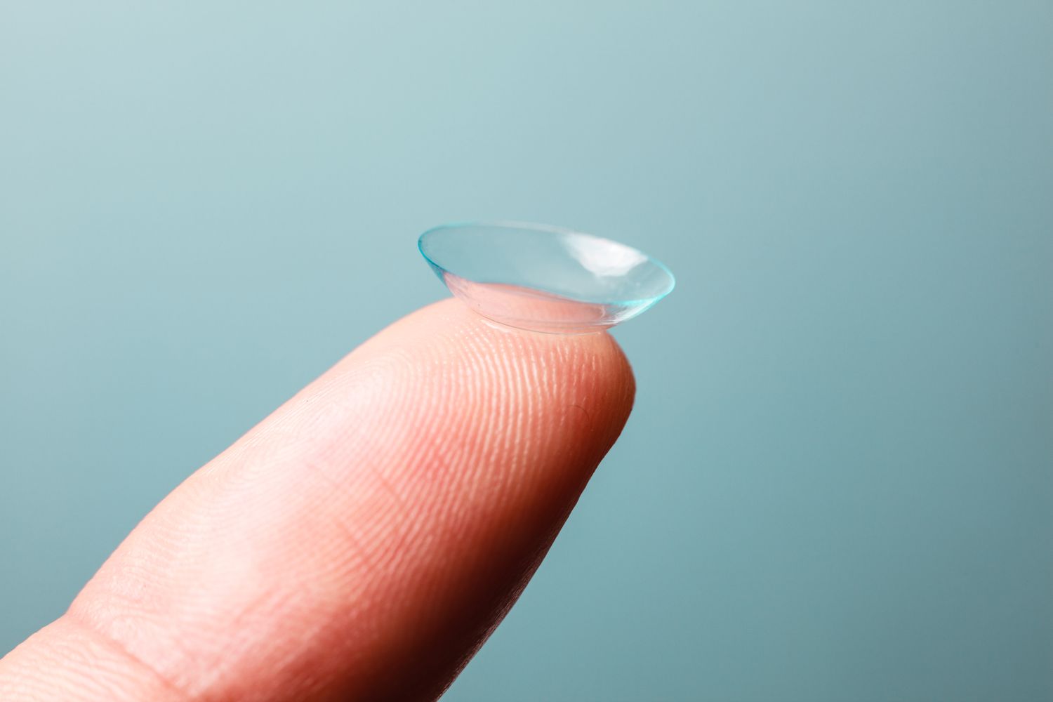 finger holding a single contact lense