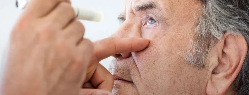 Older male with grey hair getting eyes checked for signs of cataracts