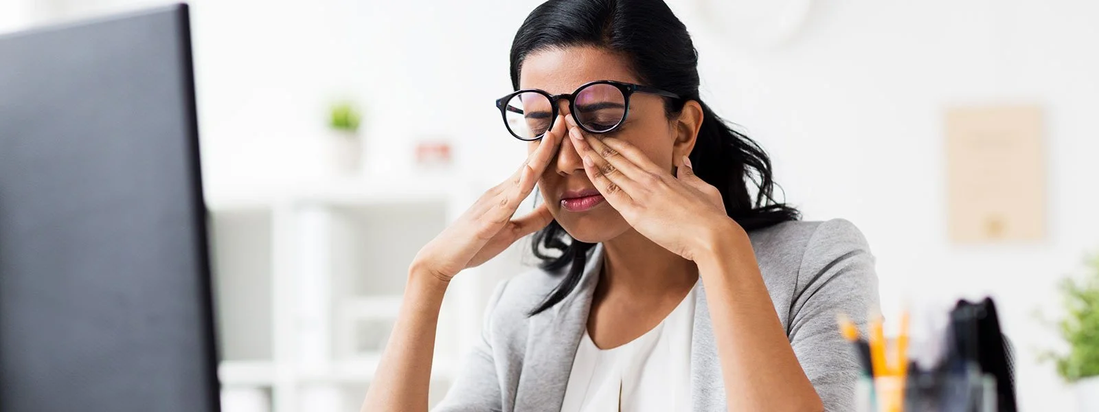 Woman looking at a computer screen and rubbing her eyes